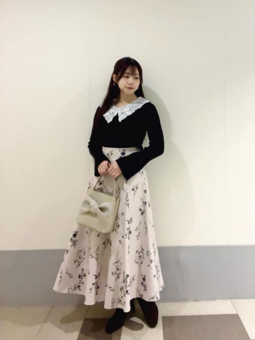 ブラック系のニット/セーター、ベージュ系のスカートを着用したレディースの秋コーディネートの2枚目の写真