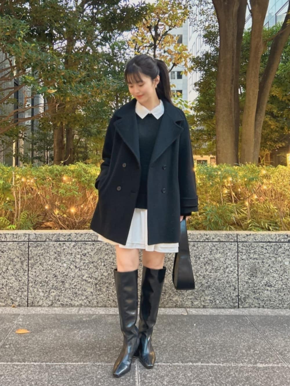 ブラック系のブーツ、ブラック系のハンドバッグ、ブラック系のピーコートを着用したレディースの冬コーディネートの2枚目の写真