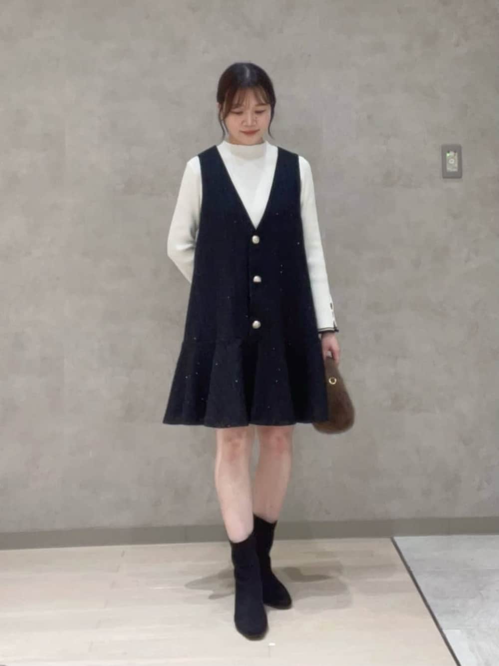 ホワイト系のニット/セーター、ブラック系のワンピース、ブラウン系のハンドバッグを着用したレディースの秋コーディネートの2枚目の写真