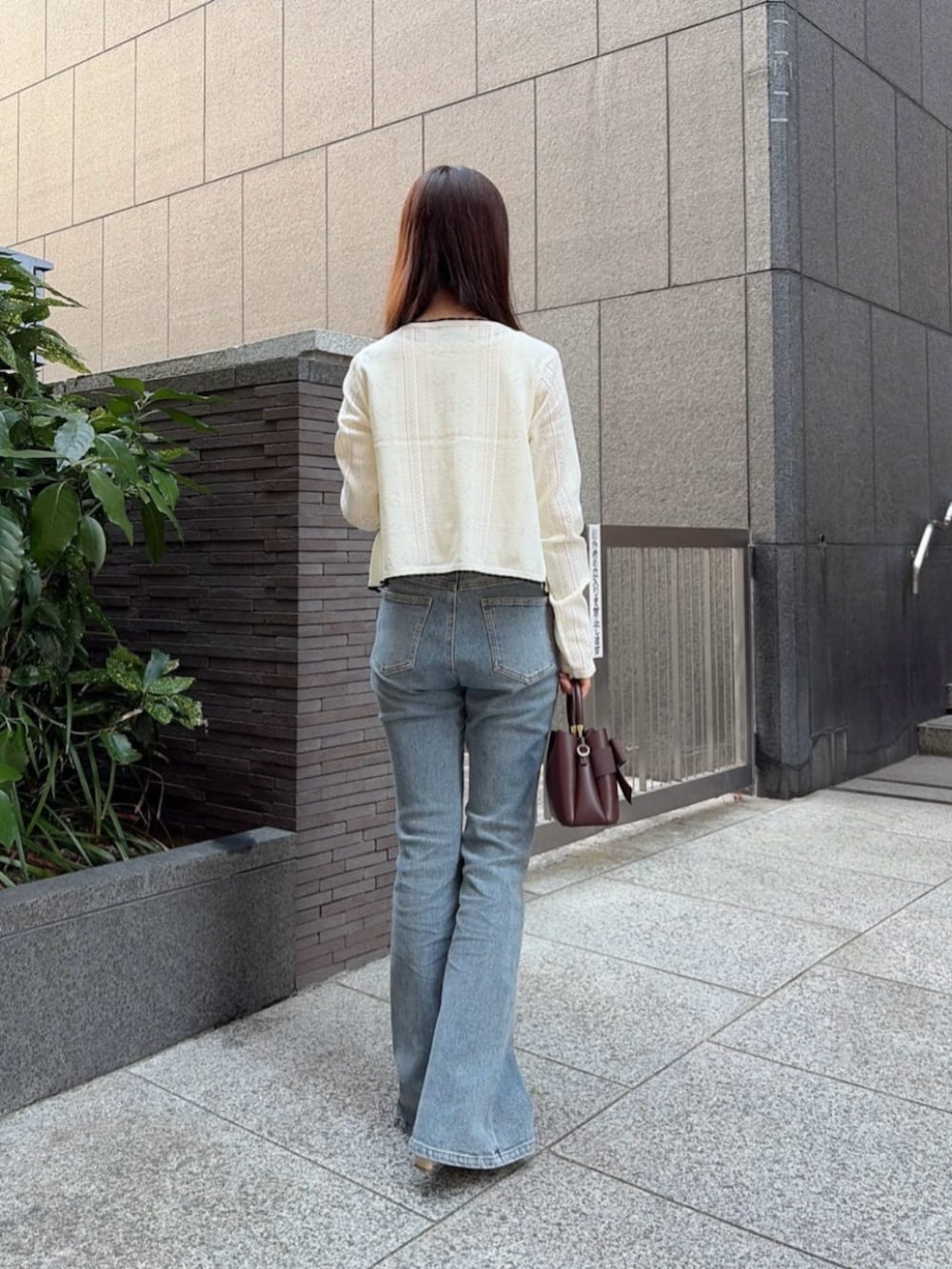 ベージュ系のパンプス、ブルー系のデニムパンツ、ブラウン系のショルダーバッグを着用したレディースの秋コーディネートの3枚目の写真