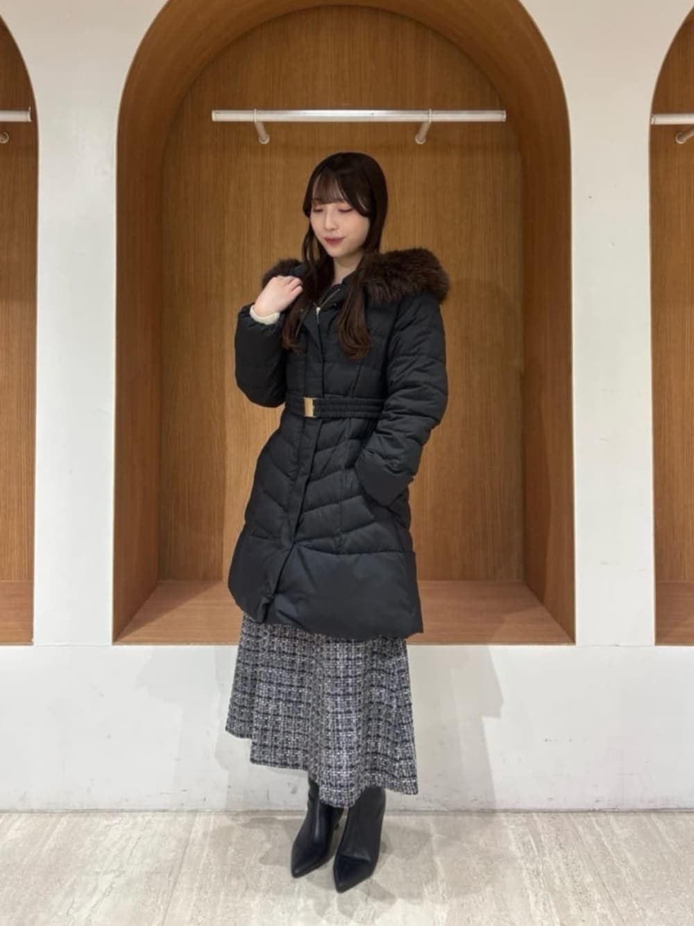 ブラック系のダウンジャケット/コート、ホワイト系のニット/セーター、ブラック系のスカートを着用したレディースの冬コーディネートの2枚目の写真