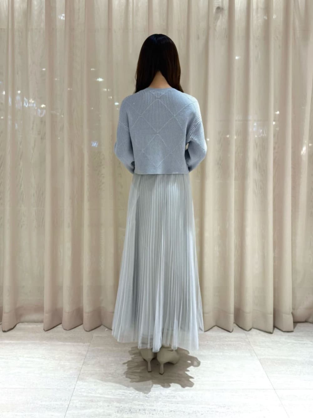 ホワイト系のショルダーバッグ、ブルー系のニット/セーター、グレー系のスカートを着用したレディースの冬コーディネートの3枚目の写真