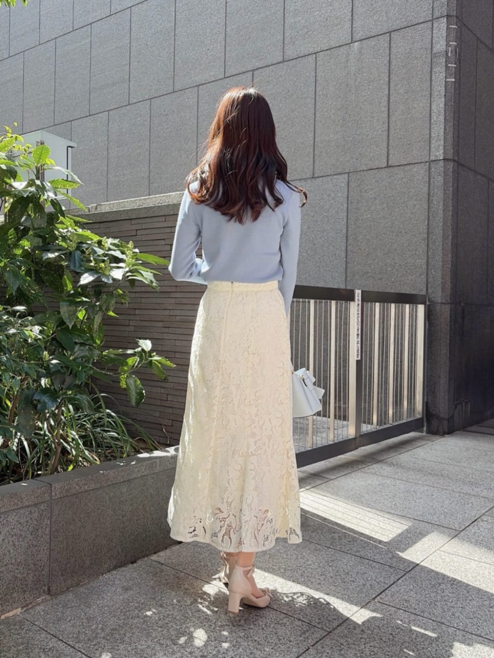 ベージュ系のパンプス、ブルー系のショルダーバッグ、ブルー系のニット/セーターを着用したレディースの春コーディネートの3枚目の写真