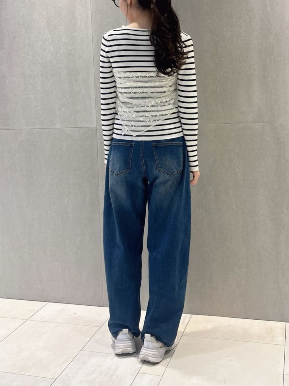 ブルー系のデニムパンツ、ホワイト系のショルダーバッグ、ホワイト系のニット/セーターを着用したレディースの春コーディネートの4枚目の写真