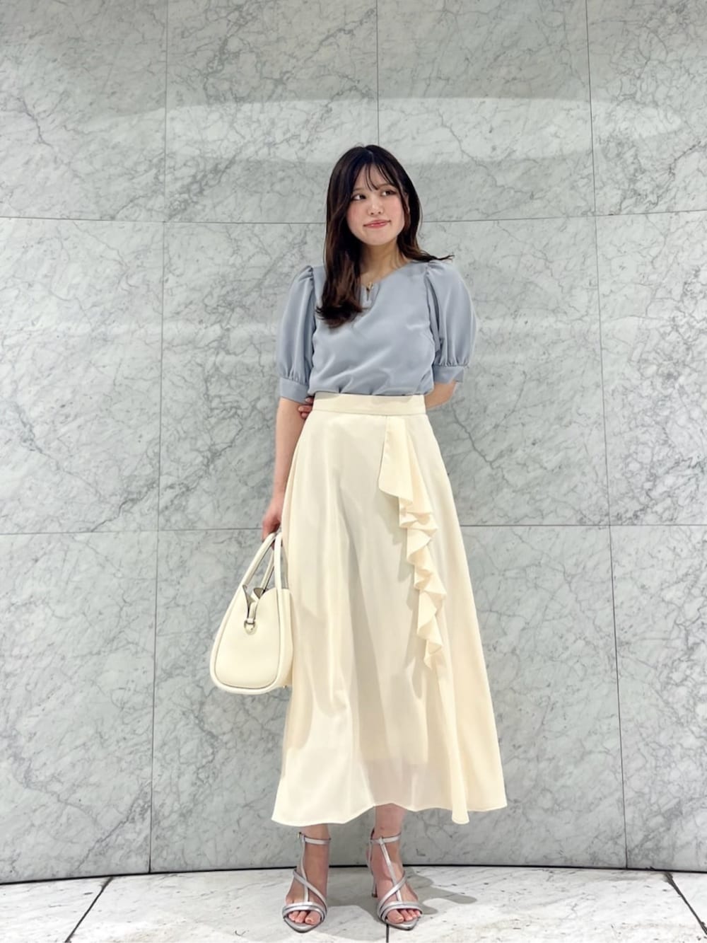 ホワイト系のショルダーバッグ、シルバー系のパンプス、ホワイト系のスカートを着用したレディースの春コーディネートの2枚目の写真