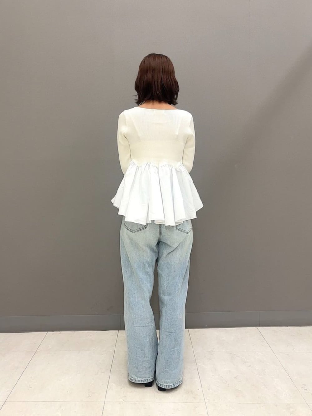 ブラウン系のショルダーバッグ、ブルー系のデニムパンツ、ホワイト系のニット/セーターを着用したレディースの秋コーディネートの4枚目の写真