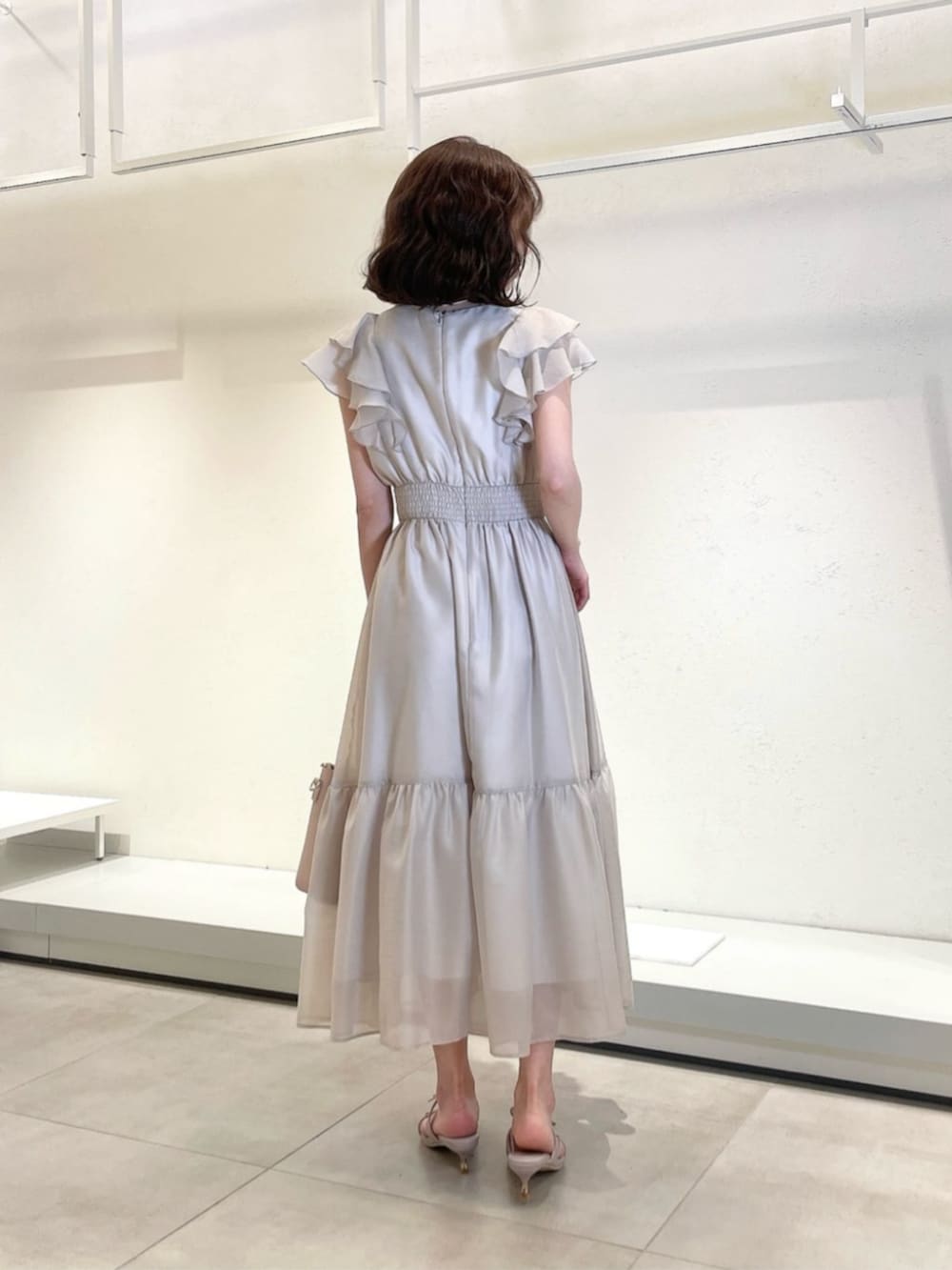 グレー系のワンピース、ピンク系のトートバッグ、パープル系のパンプスを着用したレディースの春コーディネートの3枚目の写真