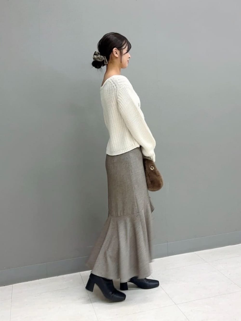 ブラウン系のハンドバッグ、ホワイト系のニット/セーター、ブラウン系のスカートを着用したレディースの冬コーディネートの3枚目の写真