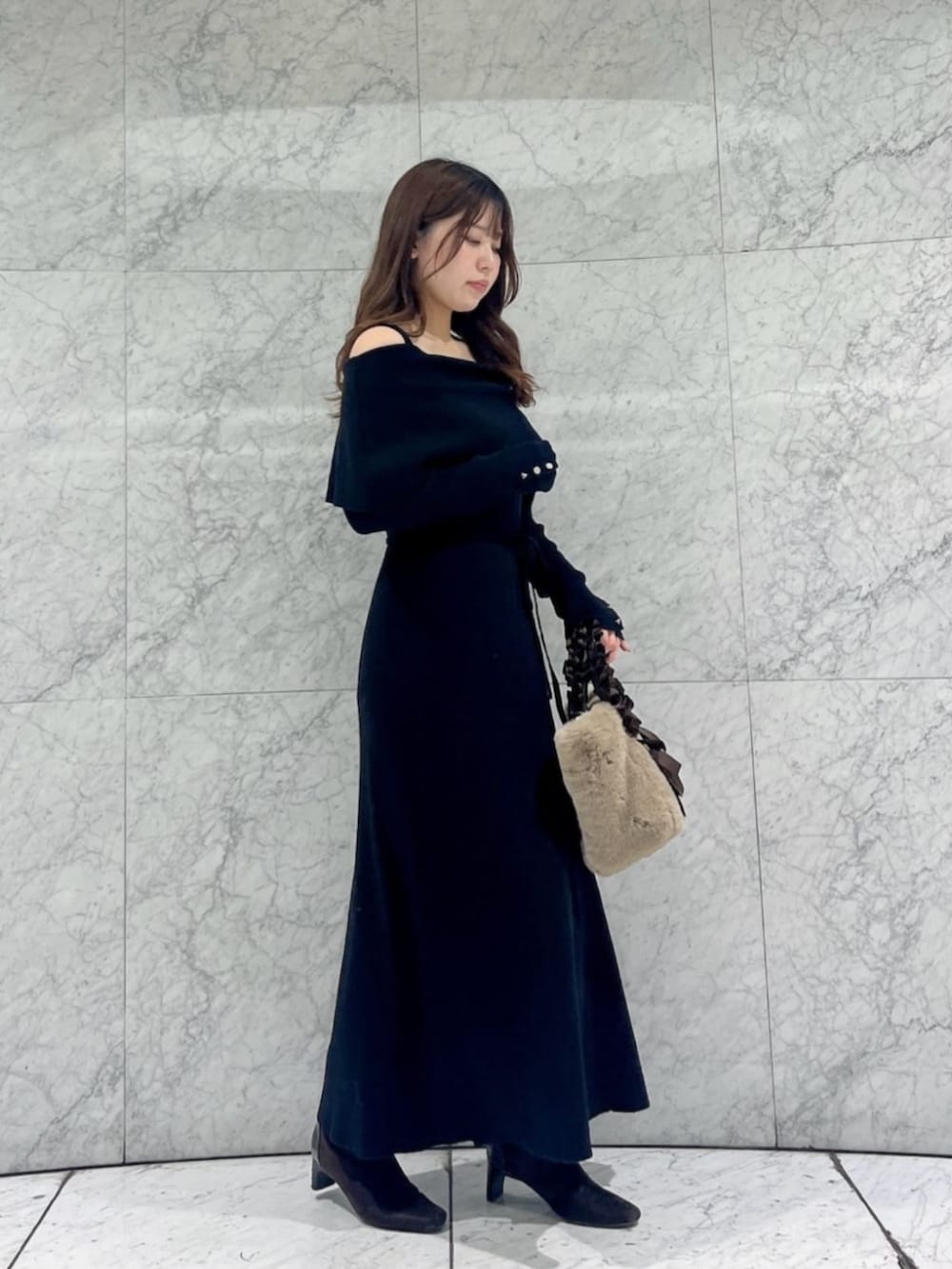 ブラック系のワンピース、ベージュ系のトートバッグを着用したレディースの冬コーディネートの3枚目の写真