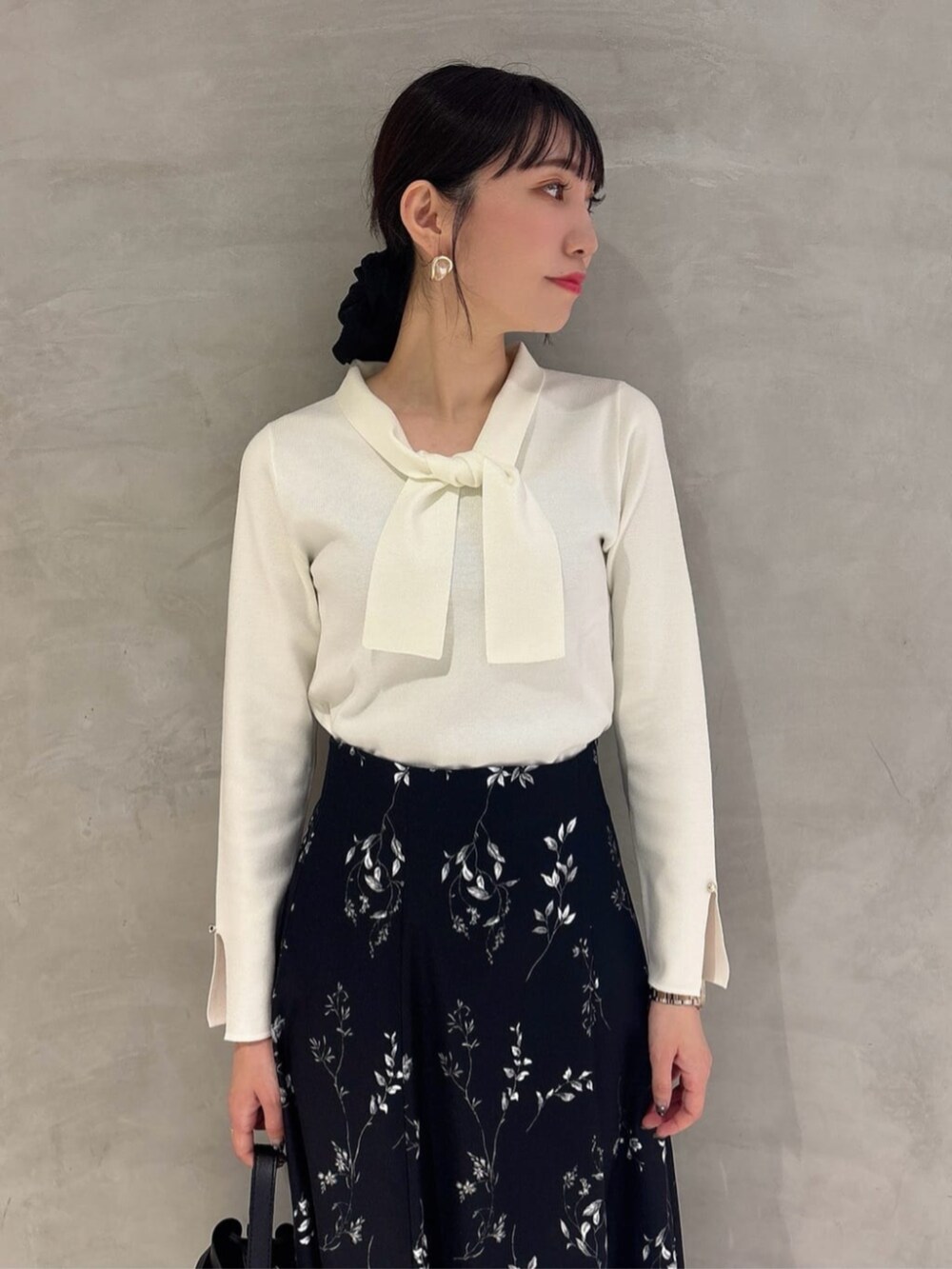 ブラック系のパンプス、ホワイト系のニット/セーター、ブラック系のスカートを着用したレディースの秋コーディネートの3枚目の写真