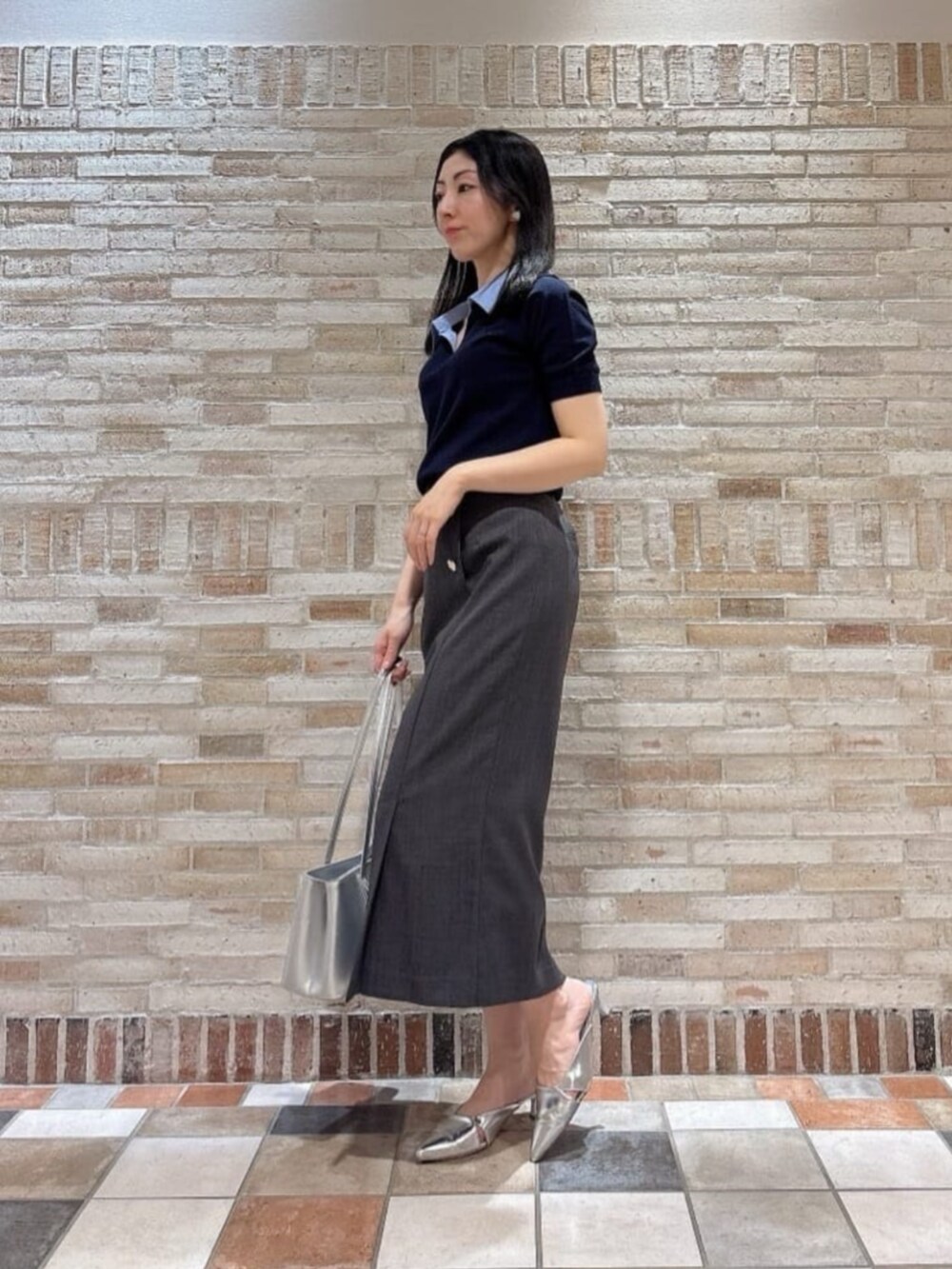 ブルー系のニット/セーター、グレー系のスカート、シルバー系のショルダーバッグを着用したレディースの春コーディネートの2枚目の写真