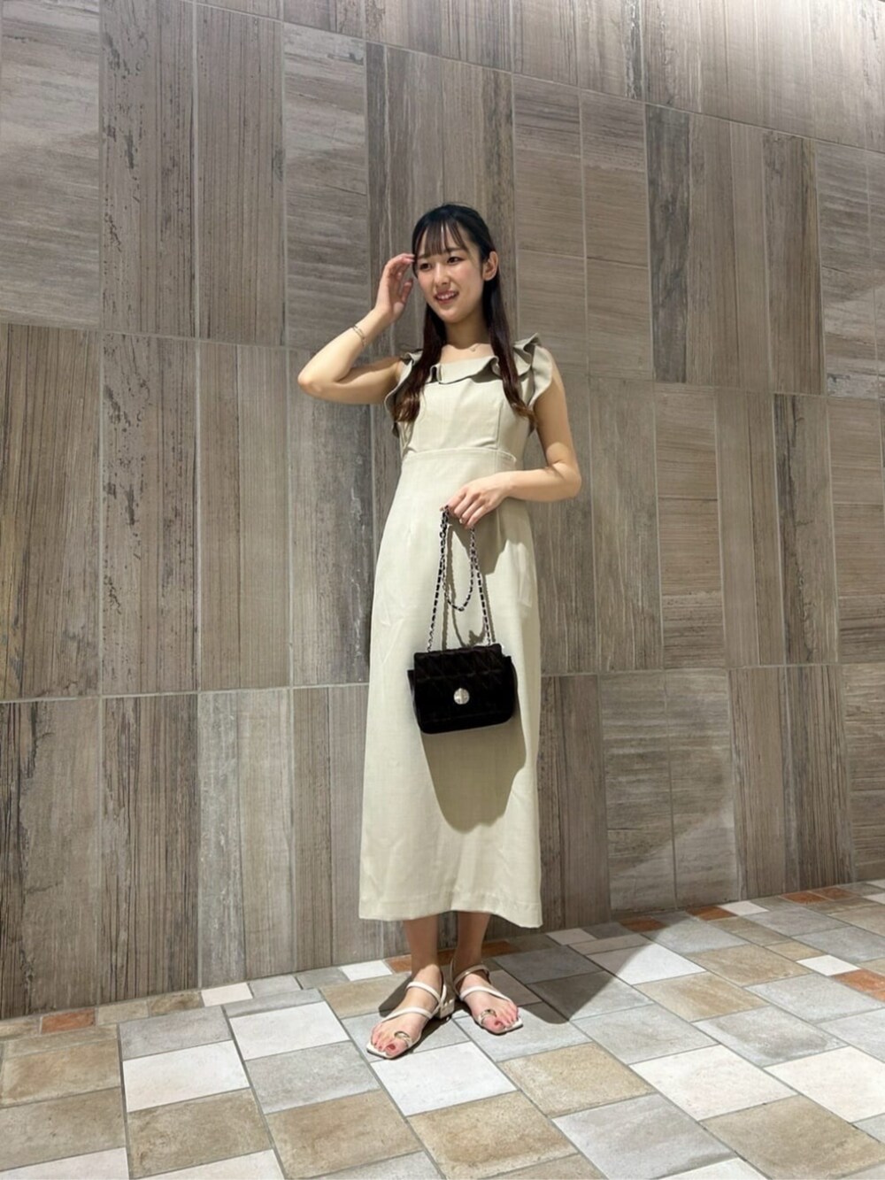 ホワイト系のパンプス、ベージュ系のワンピース、ブラウン系のショルダーバッグを着用したレディースの夏コーディネートの2枚目の写真