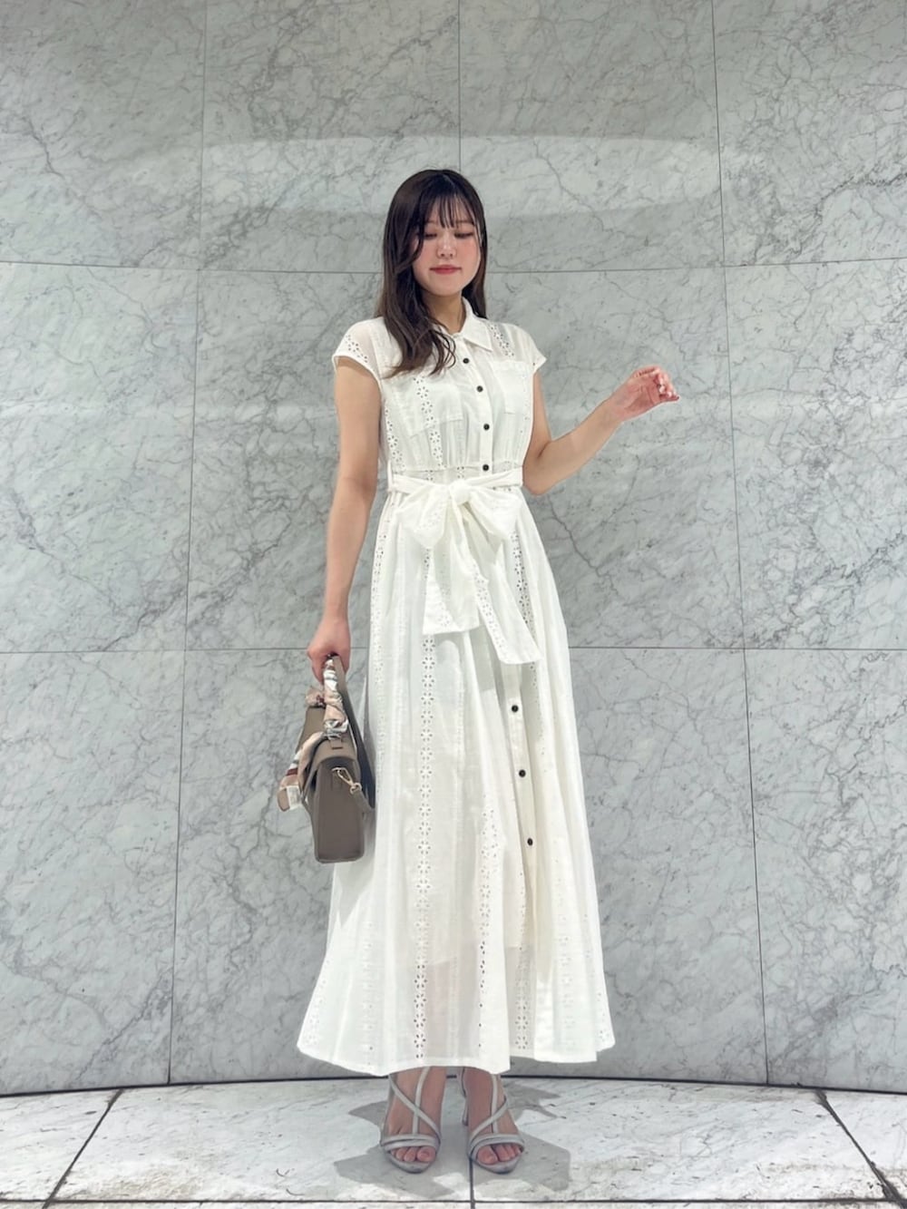 シルバー系のパンプス、ブラウン系のショルダーバッグ、ホワイト系のワンピースを着用したレディースの夏コーディネートの3枚目の写真