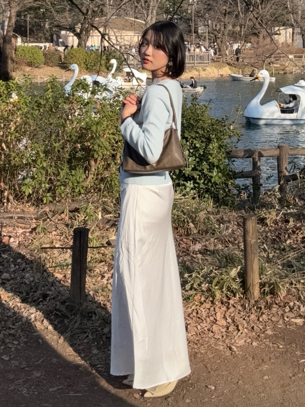 ブルー系のカーディガン/ボレロ、ホワイト系のスカート、イエロー系のパンプスを着用したレディースの春コーディネートの2枚目の写真