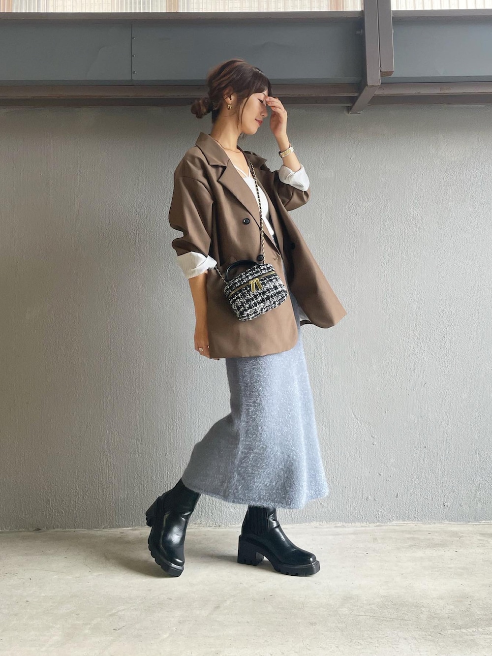 グレー系のスカート、ブラック系のブーツを着用したレディースの秋コーディネートの2枚目の写真