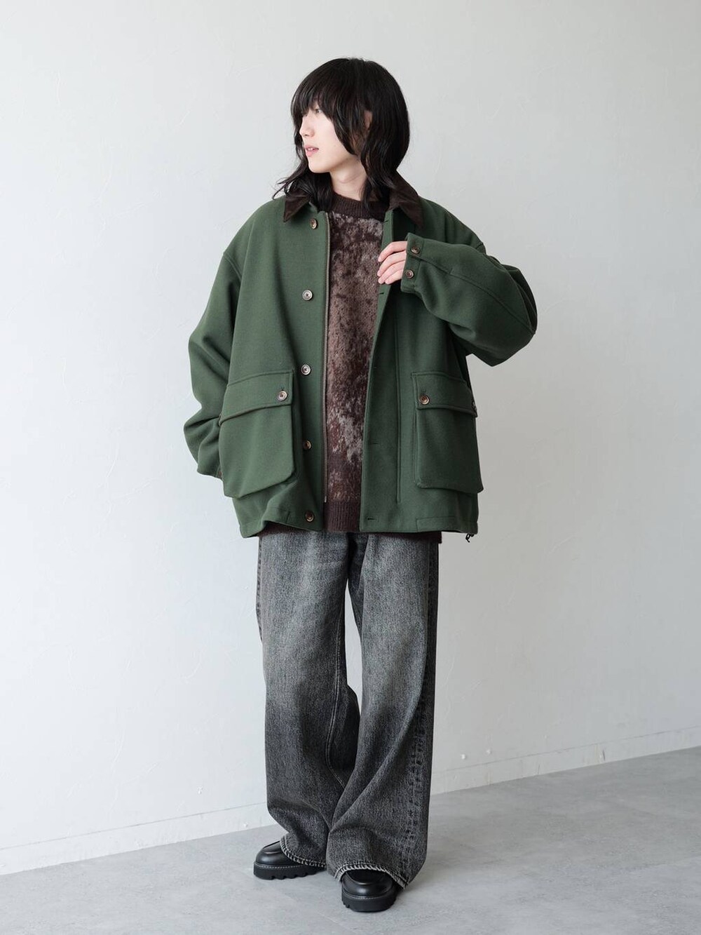 グリーン系のブルゾン、グレー系のデニムパンツ、ブラック系のドレスシューズを着用したメンズの秋コーディネートの2枚目の写真