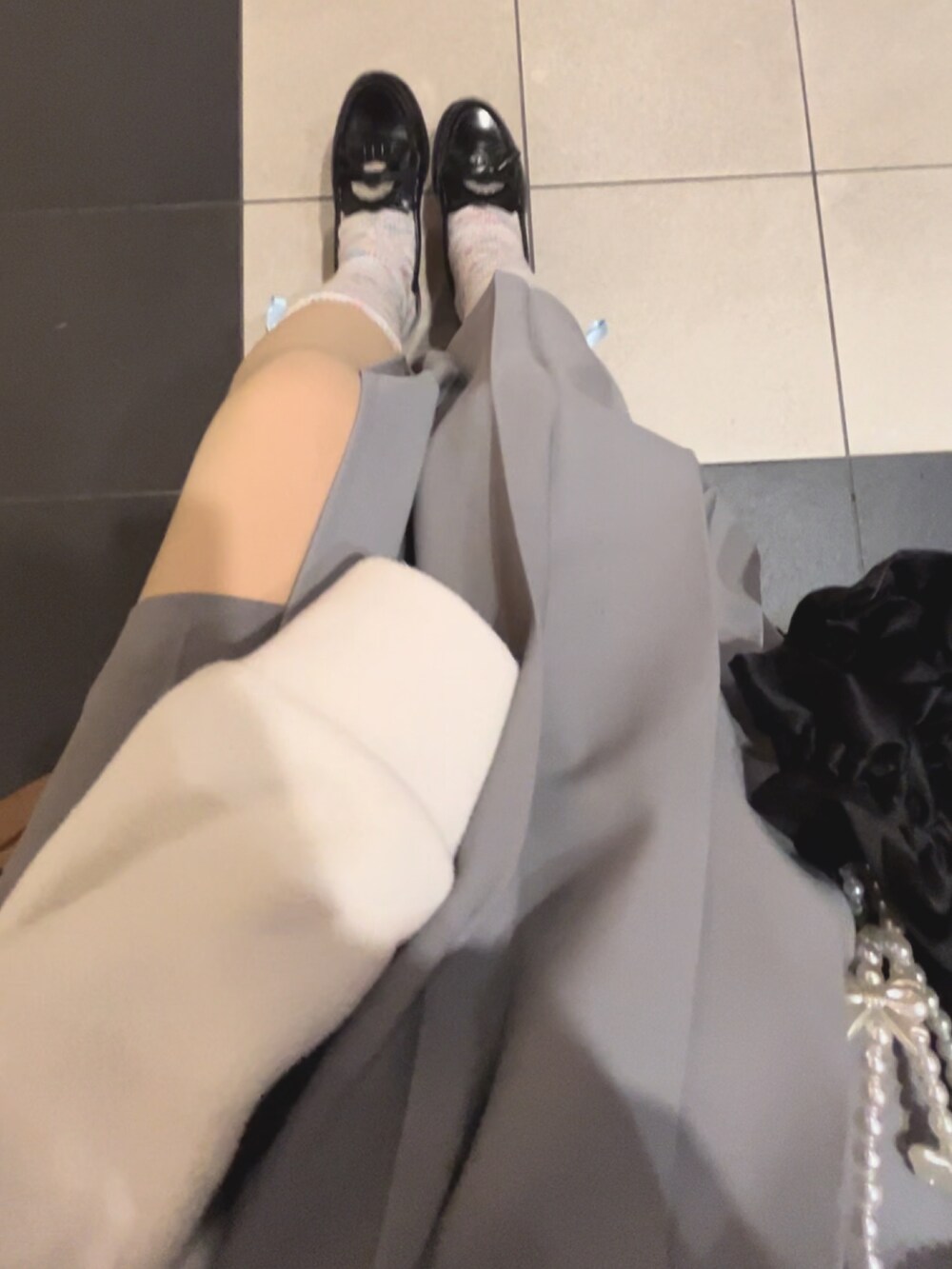 ブルー系のダッフルコート、ブラック系のニット/セーター、ホワイト系のスウェットを着用したレディースの春コーディネートの2枚目の写真