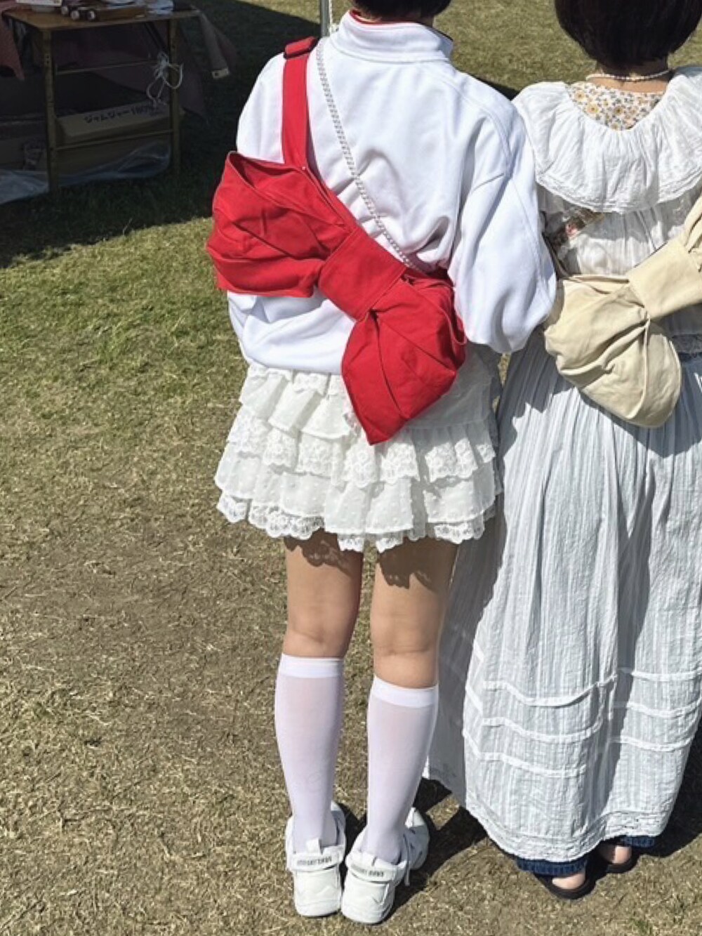 ホワイト系のスカート、ホワイト系のシューズ、レッド系のショルダーバッグを着用したレディースの春コーディネートの2枚目の写真