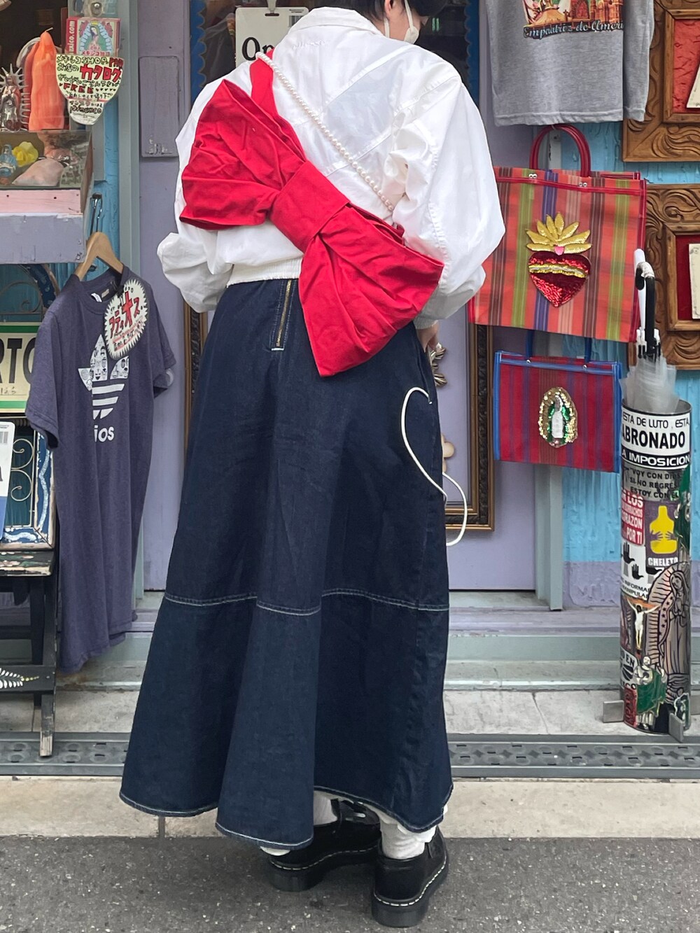 ブルー系のジャンパースカート、ホワイト系のシャツ/ブラウス、レッド系のショルダーバッグを着用したレディースの春コーディネートの2枚目の写真