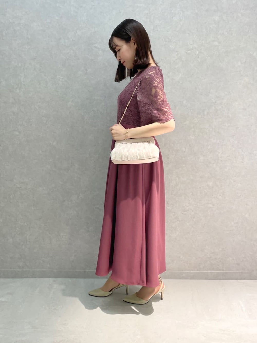 ピンク系のドレス、ベージュ系のクラッチバッグ、ベージュ系のパンプスを着用したレディースの秋コーディネートの2枚目の写真