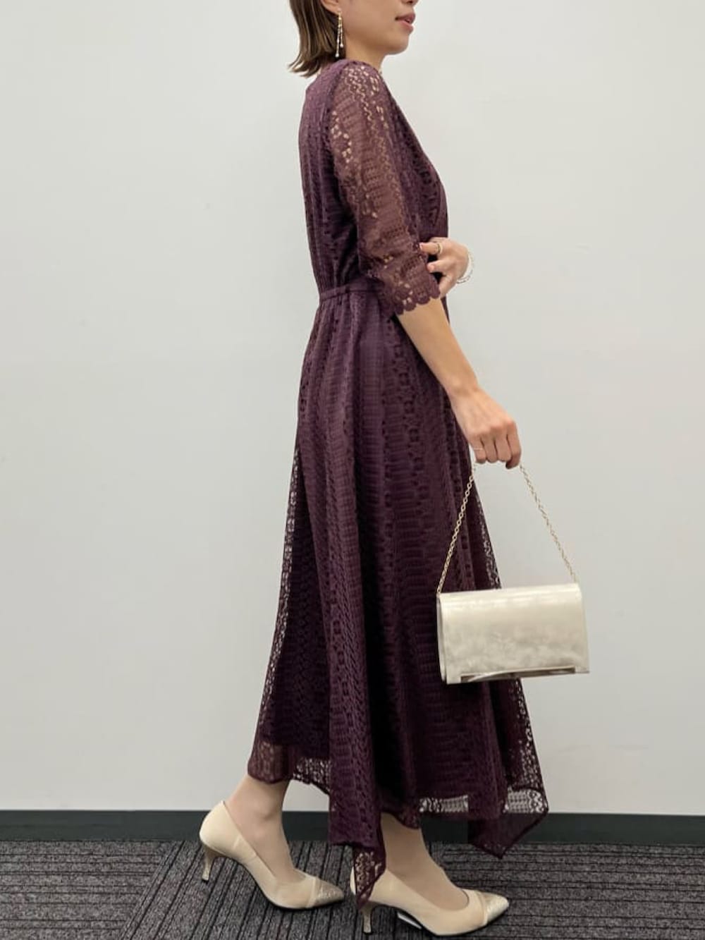 ベージュ系のクラッチバッグ、レッド系のドレス、ベージュ系のパンプスを着用したレディースの春コーディネートの2枚目の写真