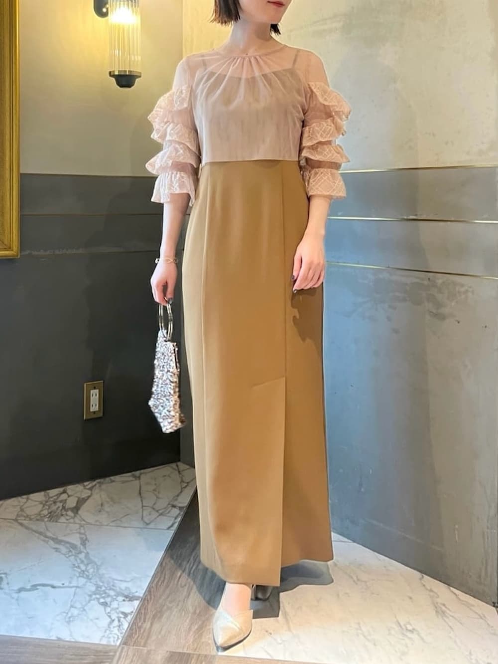 ベージュ系のノーカラージャケット、イエロー系のドレス、ベージュ系のハンドバッグを着用したレディースの冬コーディネートの2枚目の写真