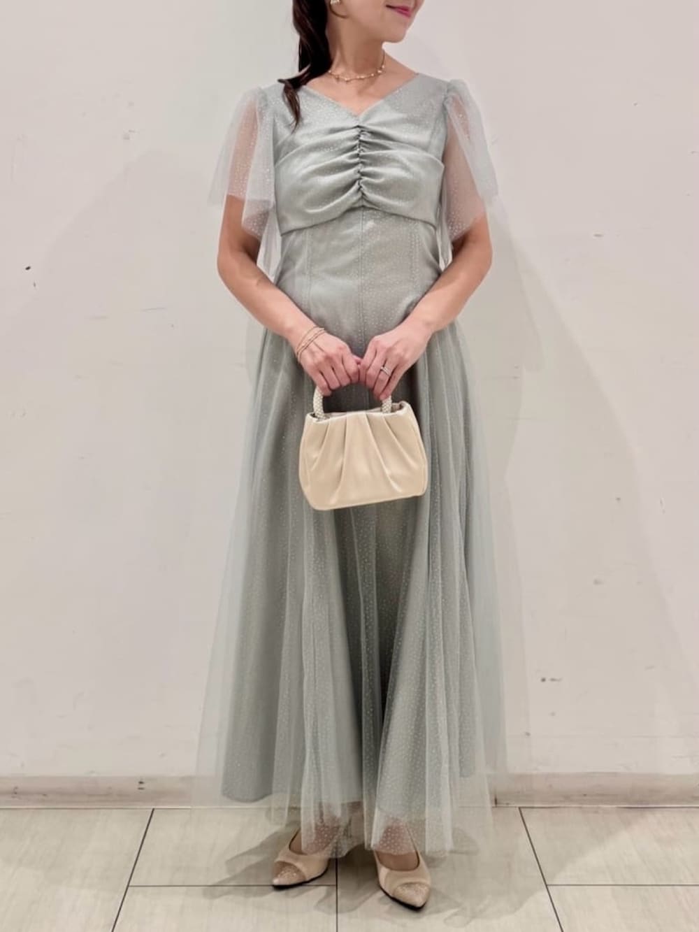 ブルー系のテーラードジャケット、シルバー系のパンプス、グリーン系のドレスを着用したレディースの秋コーディネートの2枚目の写真