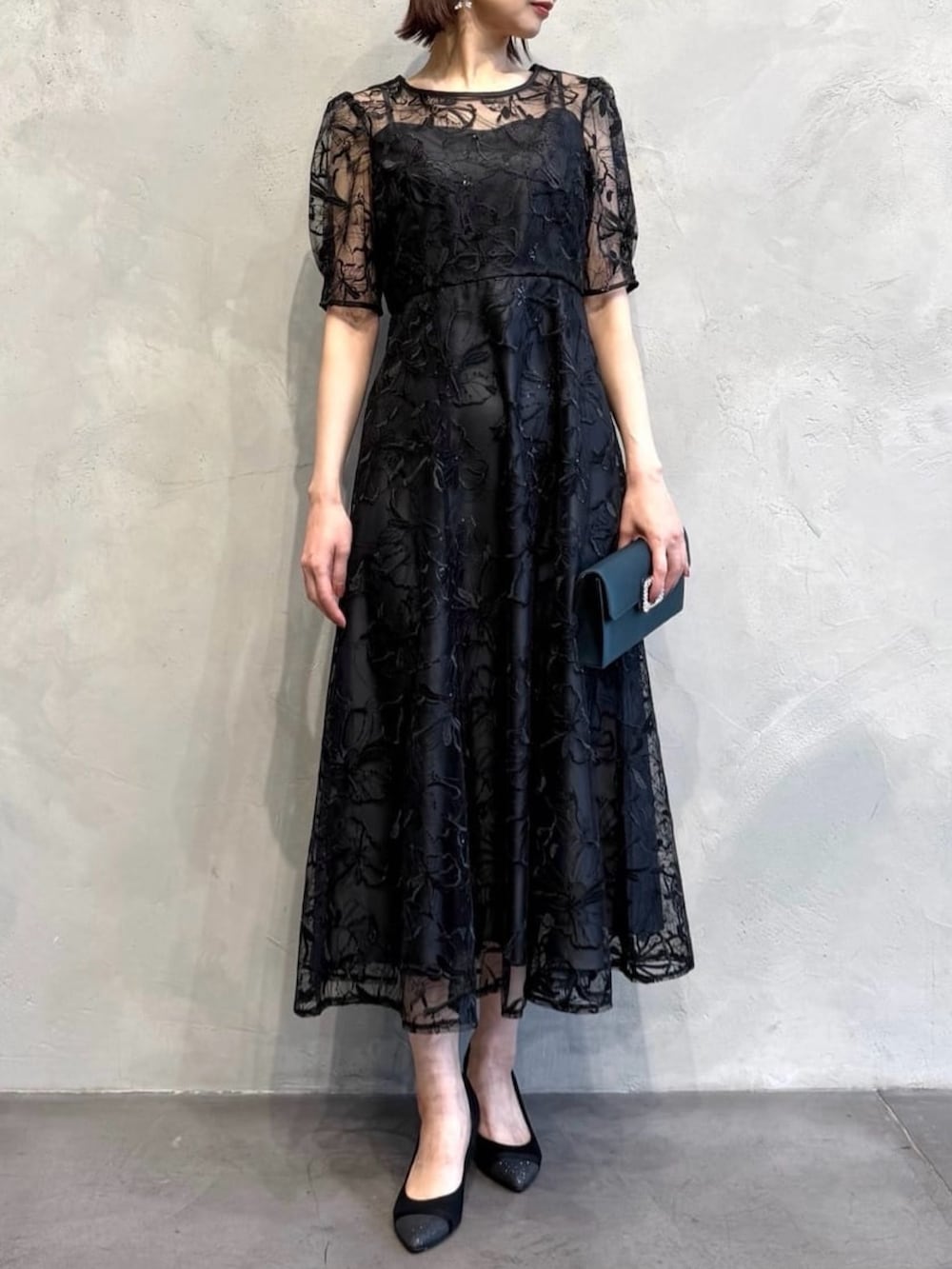 ブラック系のドレス、ブラック系のパンプス、ベージュ系のその他アウターを着用したレディースの冬コーディネートの2枚目の写真