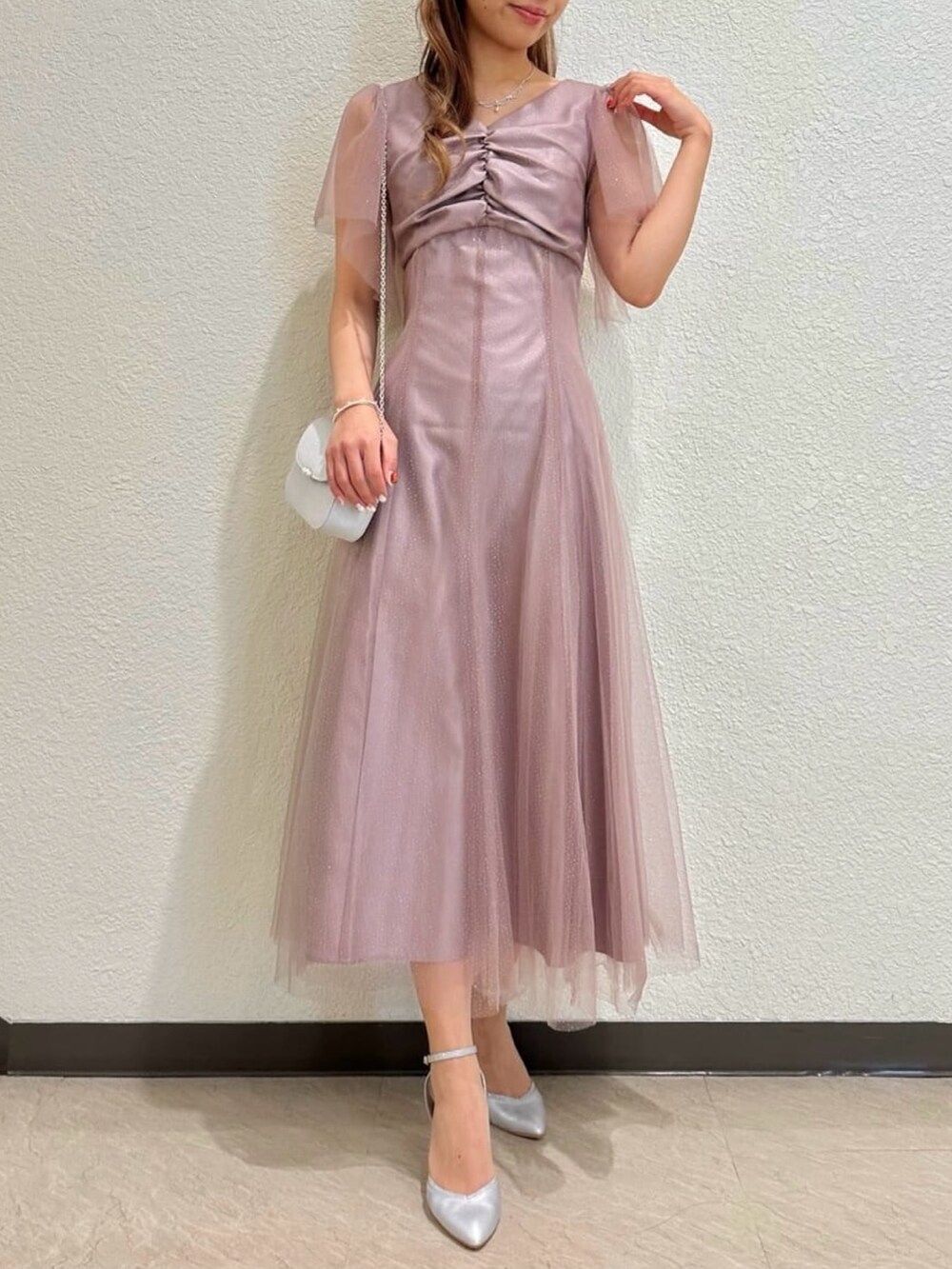 シルバー系のパンプス、ピンク系のドレス、シルバー系のクラッチバッグを着用したレディースの秋コーディネートの2枚目の写真