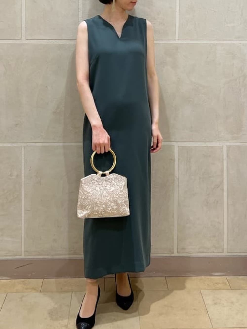 ベージュ系のハンドバッグ、ブラック系のパンプス、グリーン系のドレスを着用したレディースの夏コーディネートの2枚目の写真