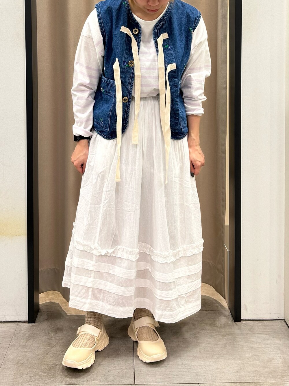 ホワイト系のスカート、パープル系のTシャツ/カットソー、ベージュ系のスニーカーを着用したレディースの春コーディネートの2枚目の写真