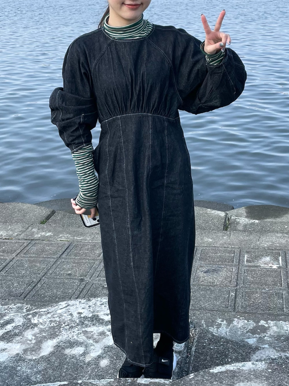 ホワイト系のステンカラーコート、ブラック系のワンピース、ブラック系のスニーカーを着用したレディースの春コーディネートの3枚目の写真