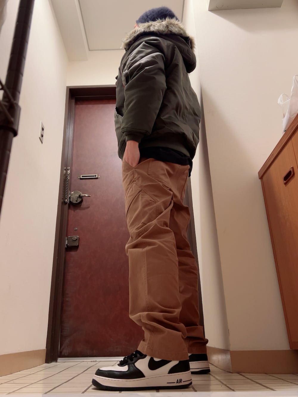 ブラック系のスニーカー、ブラウン系のカーゴパンツ、グリーン系のミリタリージャケットを着用したメンズの秋コーディネートの2枚目の写真