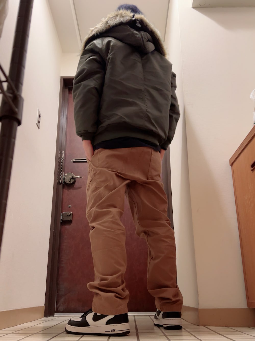 ブラック系のスニーカー、ブラウン系のカーゴパンツ、グリーン系のミリタリージャケットを着用したメンズの秋コーディネートの3枚目の写真