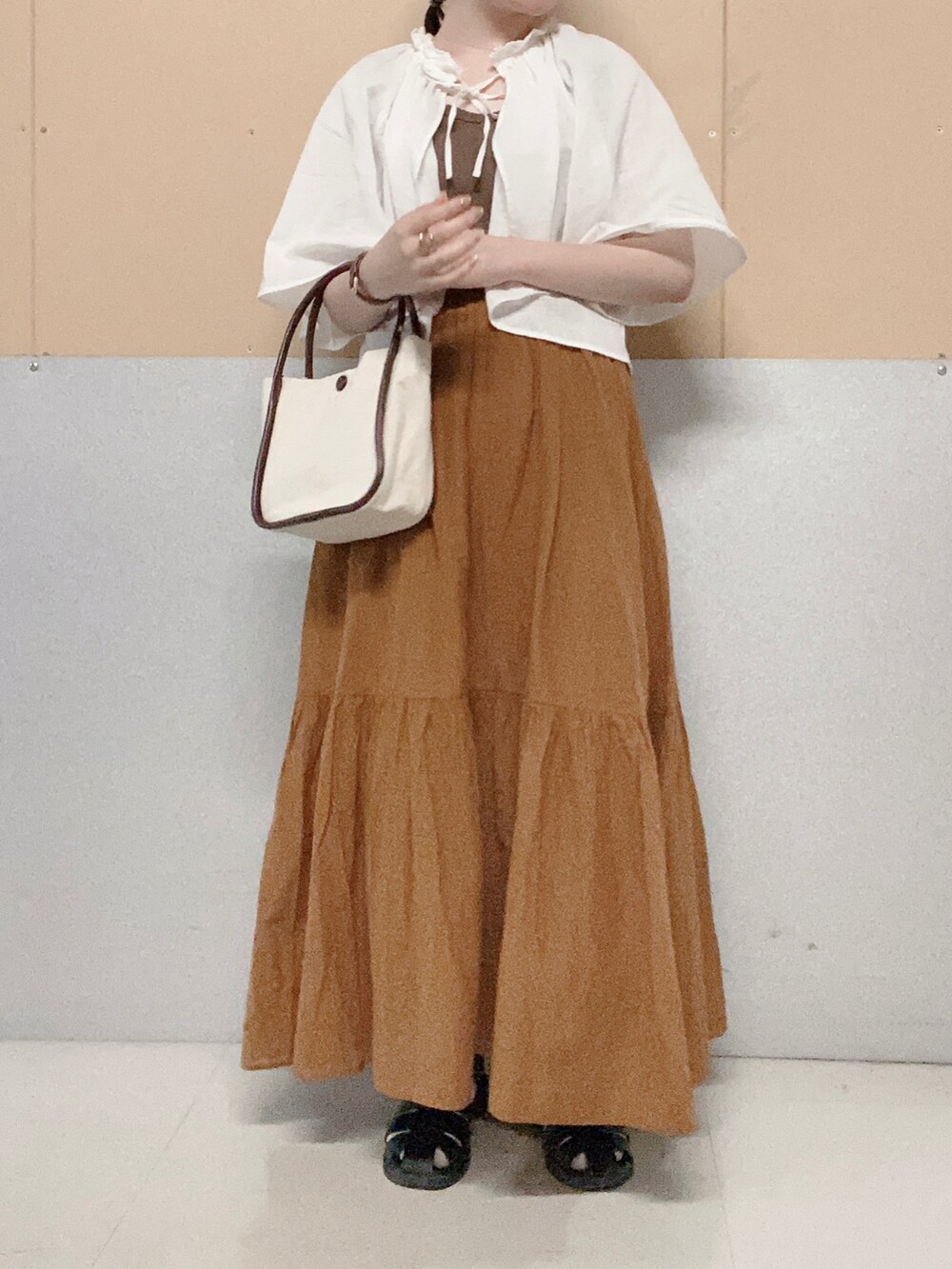 ブラウン系のハンドバッグ、ブラック系のサンダル、イエロー系のスカートを着用したレディースの夏コーディネートの2枚目の写真