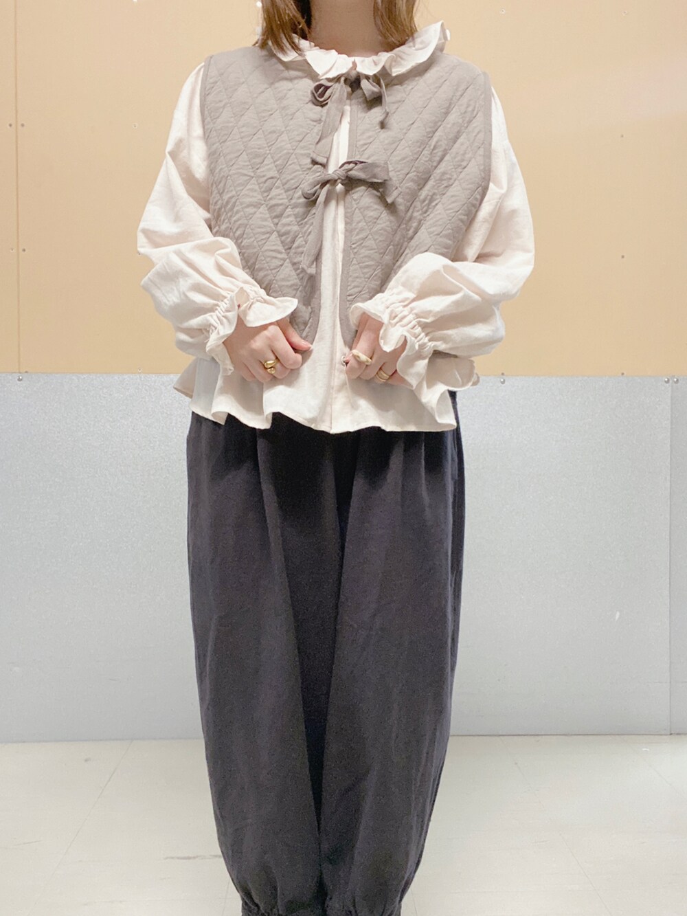 ピンク系のシャツ/ブラウス、ベージュ系のベスト、ブラック系のその他パンツを着用したレディースの秋コーディネートの2枚目の写真