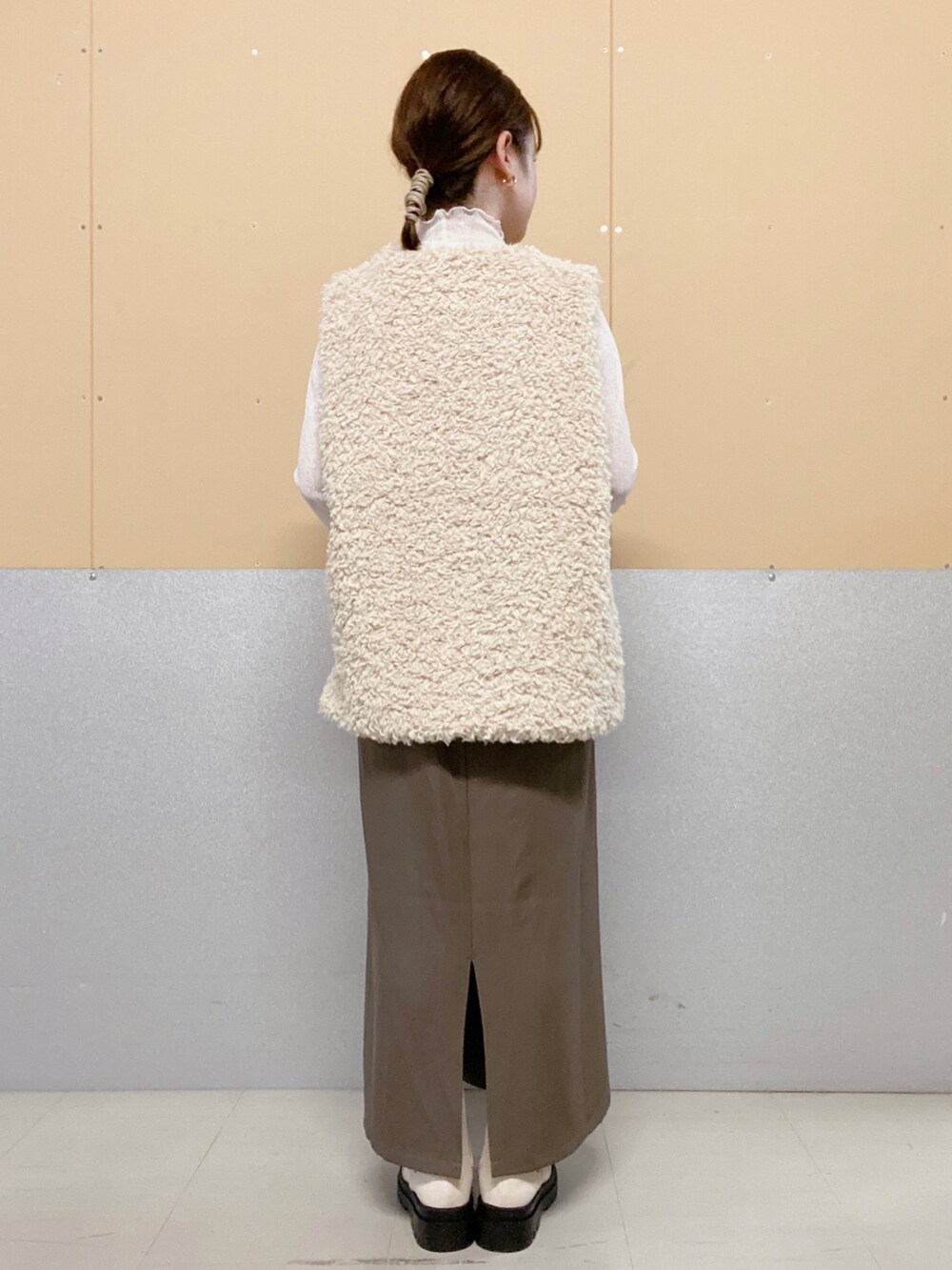 ホワイト系のブーツ、グレー系のワンピース、ホワイト系のベストを着用したレディースの秋コーディネートの2枚目の写真