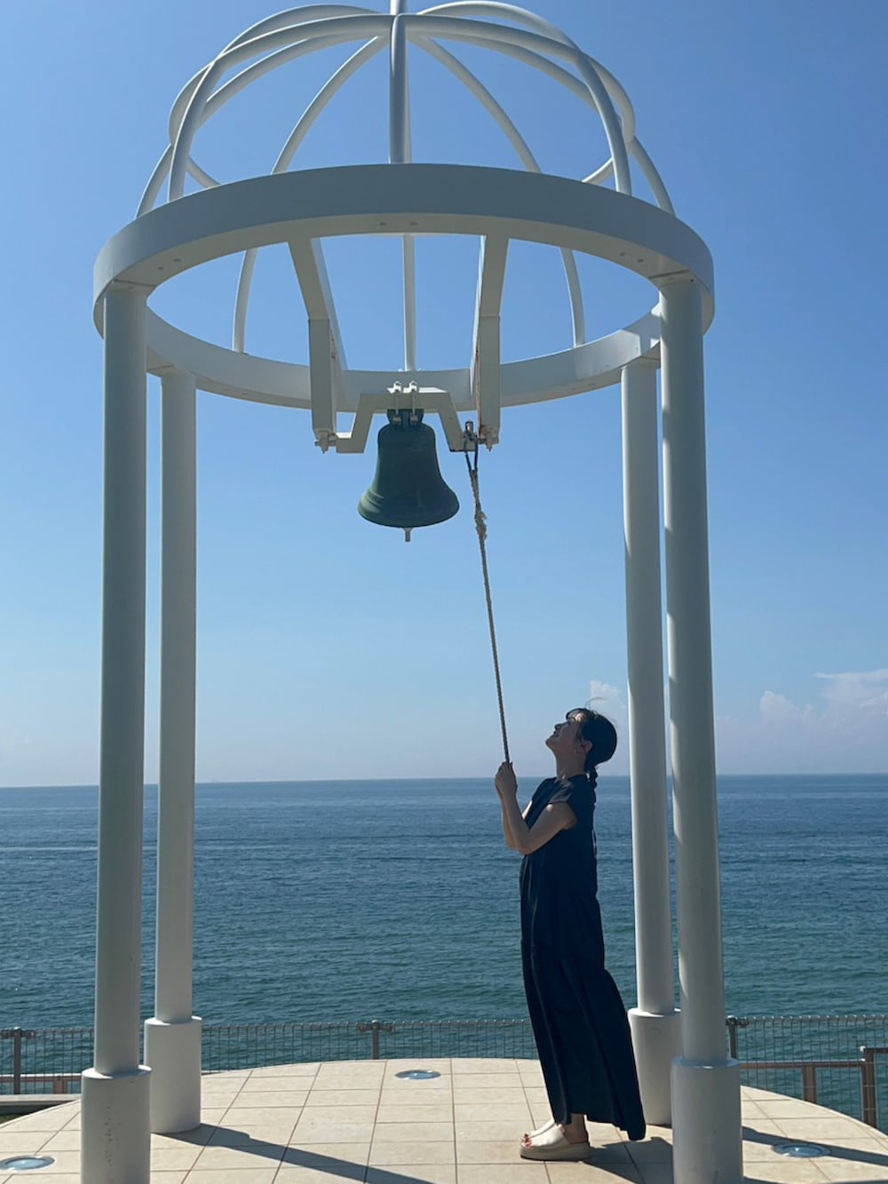 グレー系のワンピース、ホワイト系のサンダルを着用したレディースの秋コーディネートの2枚目の写真