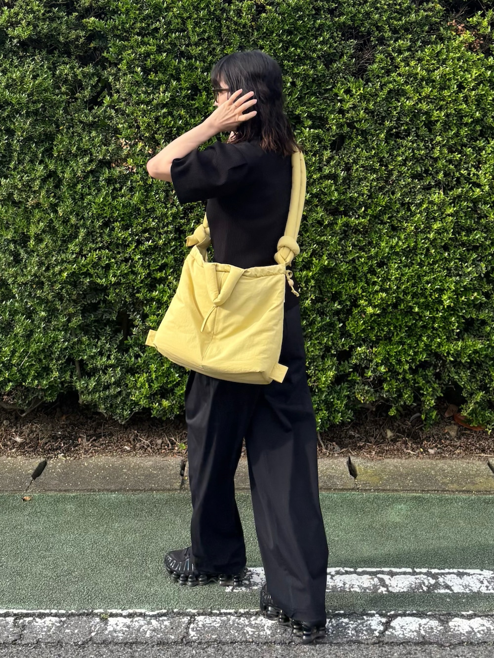 ブラック系のカーディガン/ボレロ、ブラック系のスニーカー、イエロー系のハンドバッグを着用したレディースの夏コーディネートの2枚目の写真