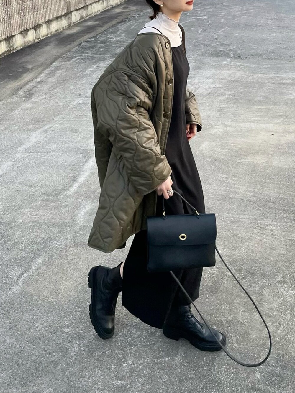 ブラック系のワンピース、グリーン系のノーカラーコートを着用したレディースの冬コーディネートの2枚目の写真