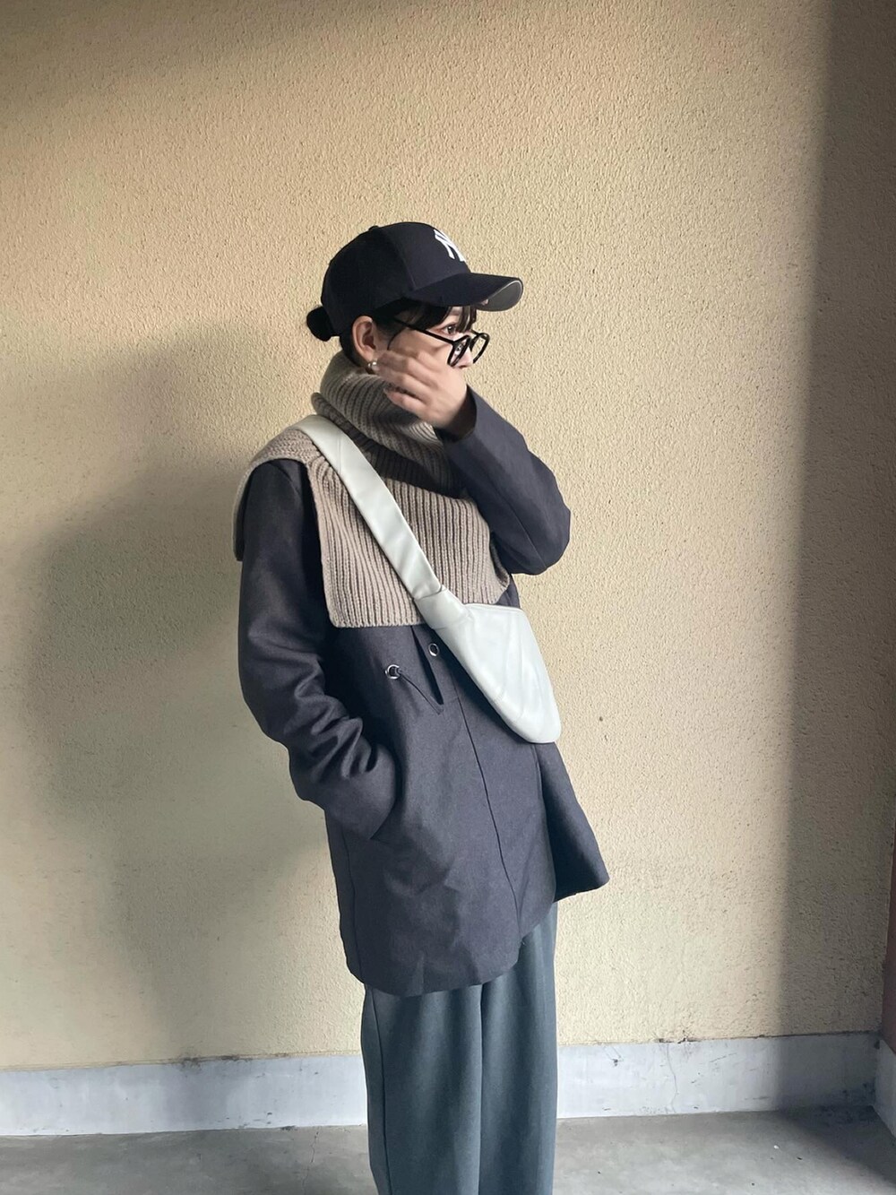 グレー系のノーカラーコート、ブラウン系のネックウォーマー/スヌードを着用したレディースの冬コーディネートの2枚目の写真