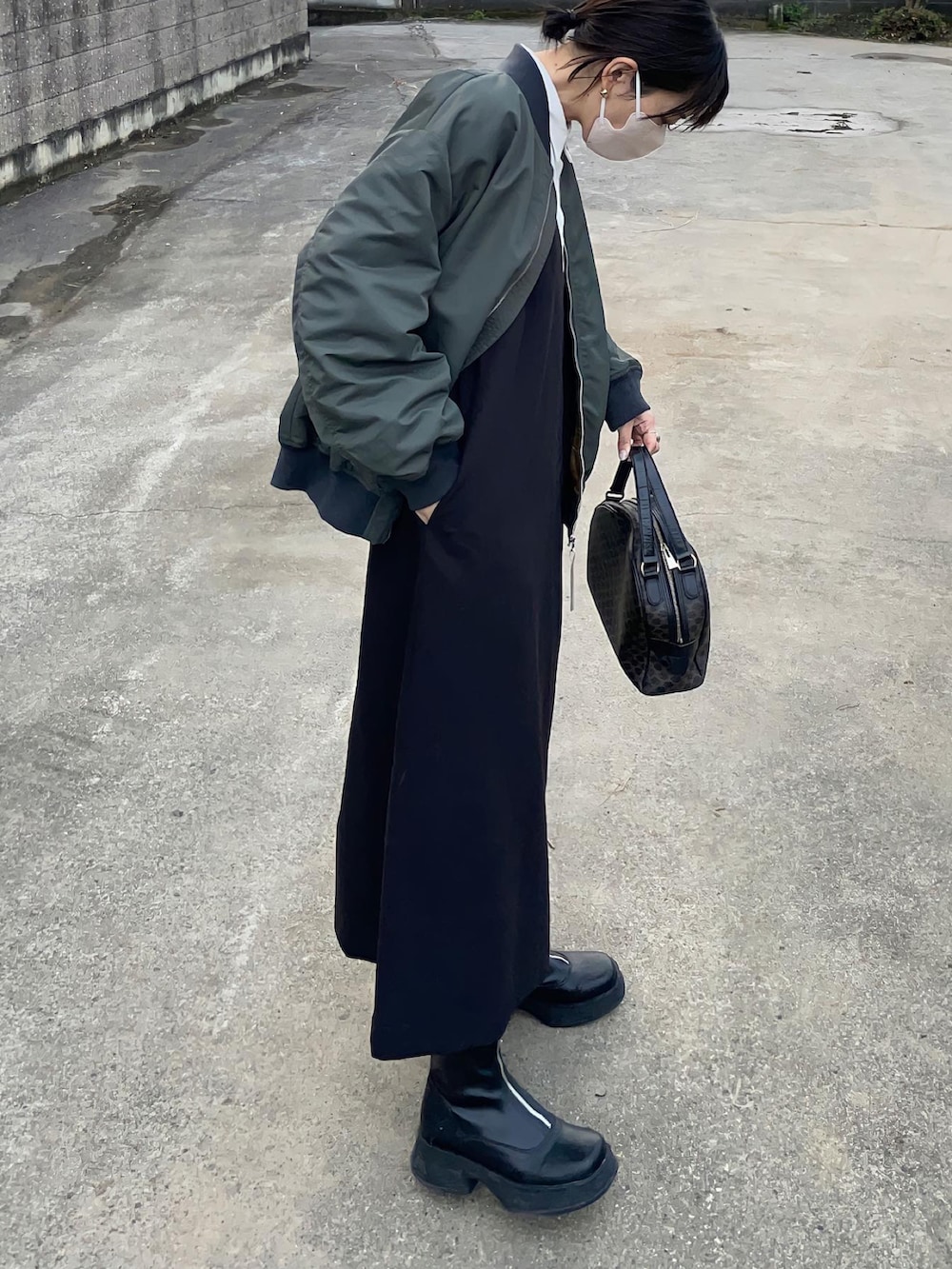 グリーン系のMA-1、ブラック系のジャンパースカートを着用したレディースの秋コーディネートの2枚目の写真