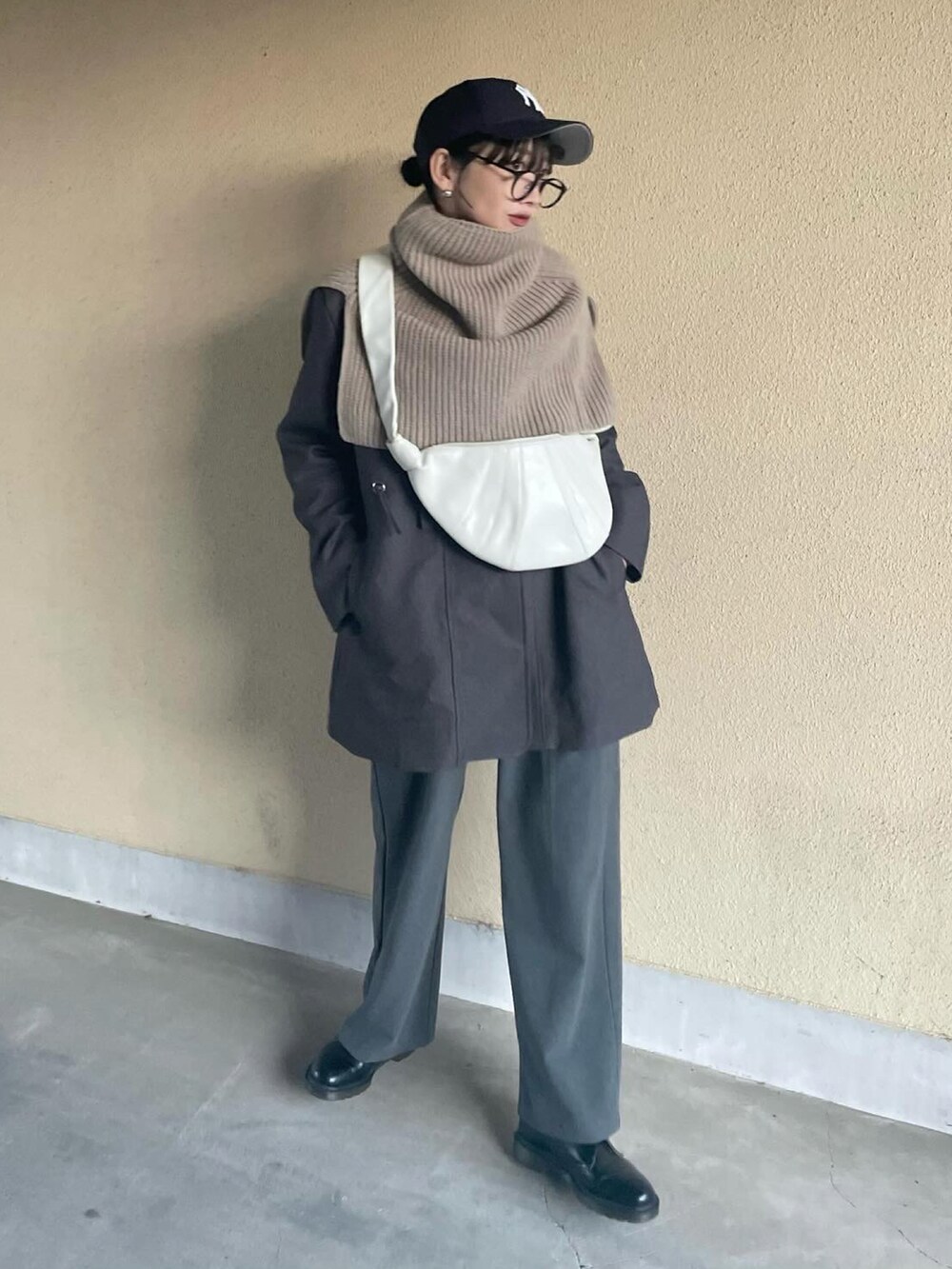 グレー系のノーカラーコート、ブラウン系のネックウォーマー/スヌードを着用したレディースの冬コーディネートの3枚目の写真