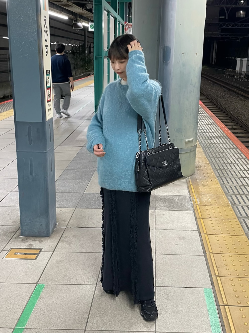 ブルー系のニット/セーター、ブルー系のスカート、ブラック系のスニーカーを着用したレディースの秋コーディネートの2枚目の写真