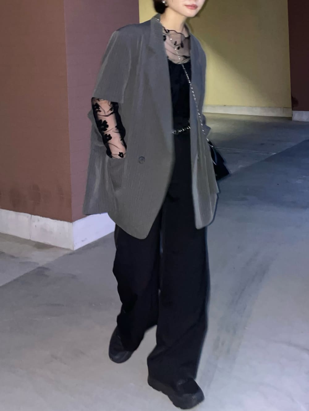 グレー系のテーラードジャケット、ブラック系のショルダーバッグ、ブラック系のスニーカーを着用したレディースの夏コーディネートの3枚目の写真