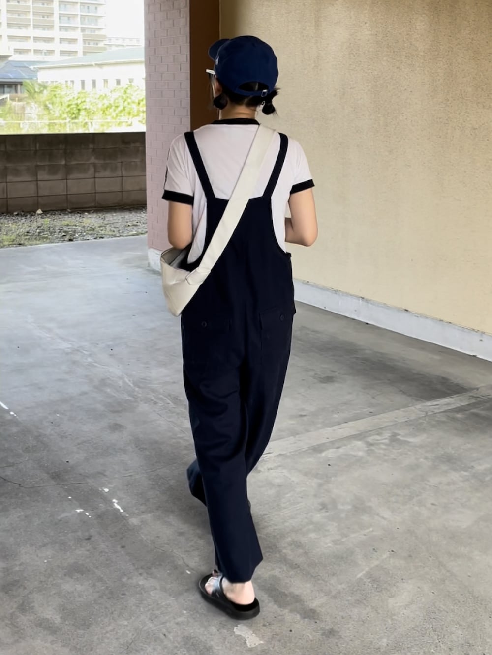 ブルー系のサロペット/オーバーオール、ホワイト系のTシャツ/カットソー、ブラック系のサンダルを着用したレディースの夏コーディネートの2枚目の写真