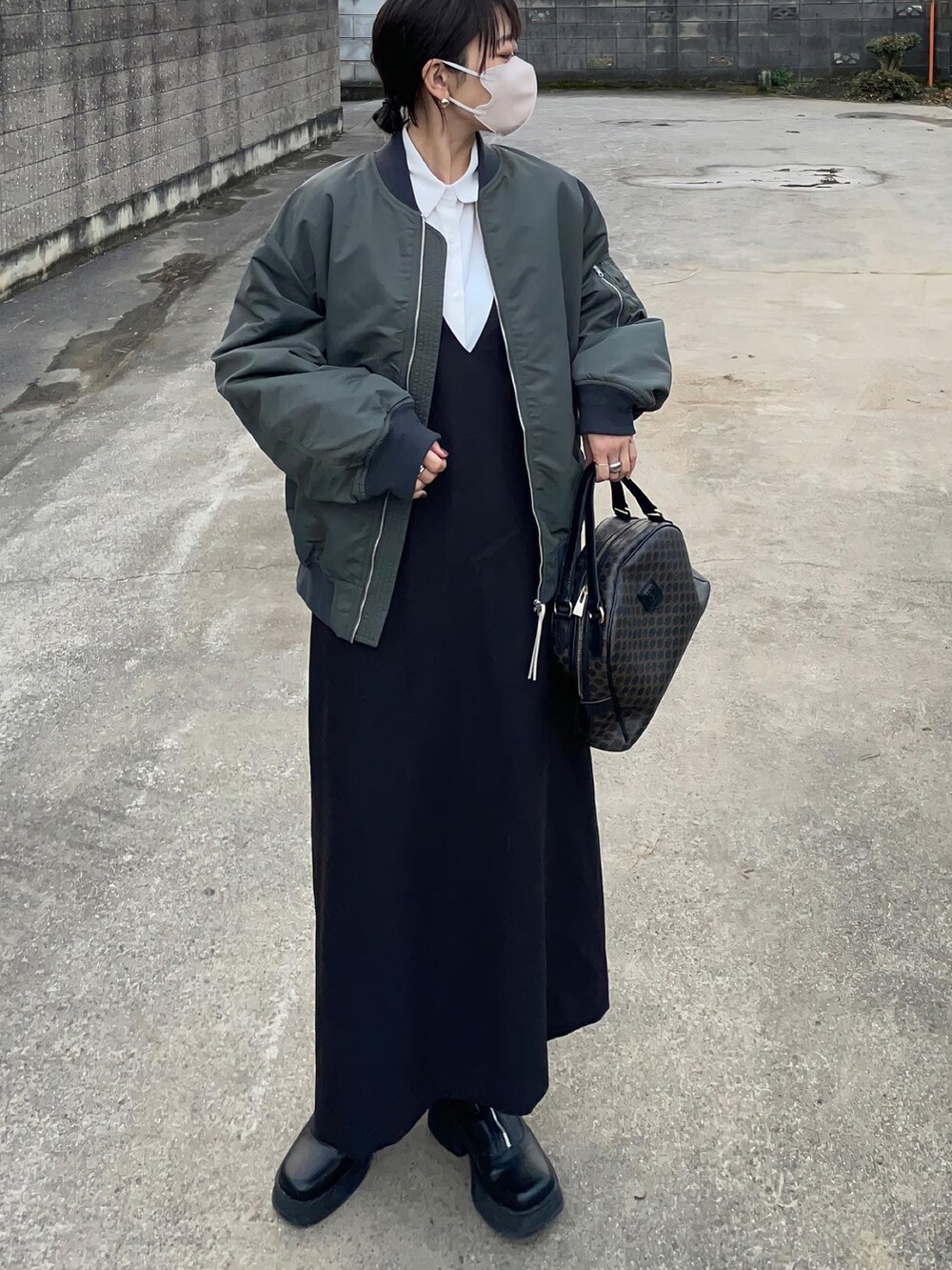 グリーン系のMA-1、ブラック系のジャンパースカートを着用したレディースの秋コーディネートの3枚目の写真