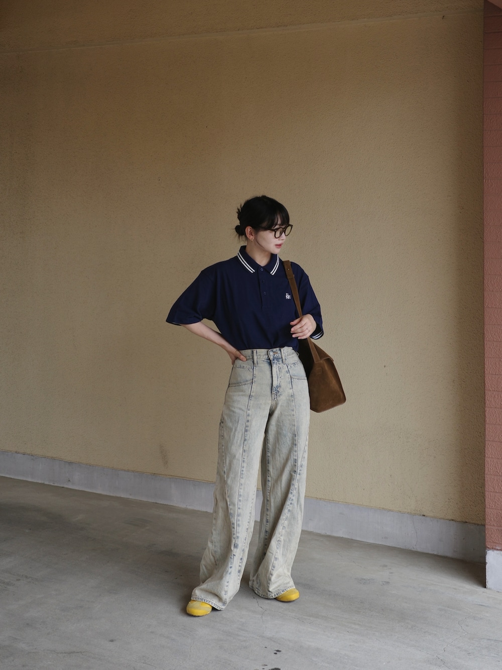 ブルー系のポロシャツ、ブルー系のデニムパンツ、イエロー系のショルダーバッグを着用したレディースの春コーディネートの3枚目の写真