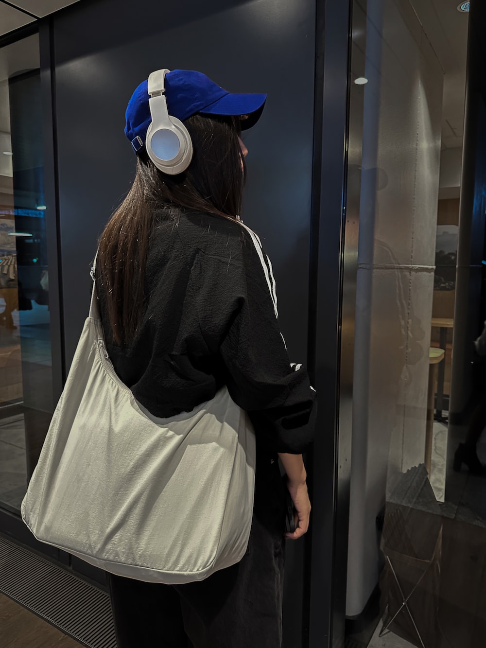 ブラック系のブルゾン、ブラック系のデニムパンツ、ホワイト系のショルダーバッグを着用したレディースの秋コーディネートの3枚目の写真