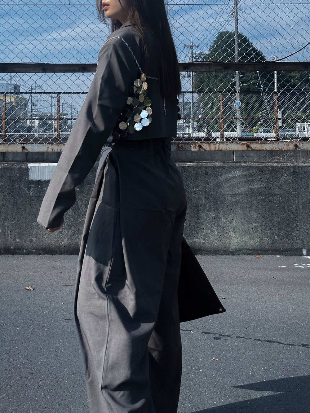 グレー系のセットアップ、ブラック系のハンドバッグ、シルバー系のファッション雑貨を着用したレディースの冬コーディネートの2枚目の写真